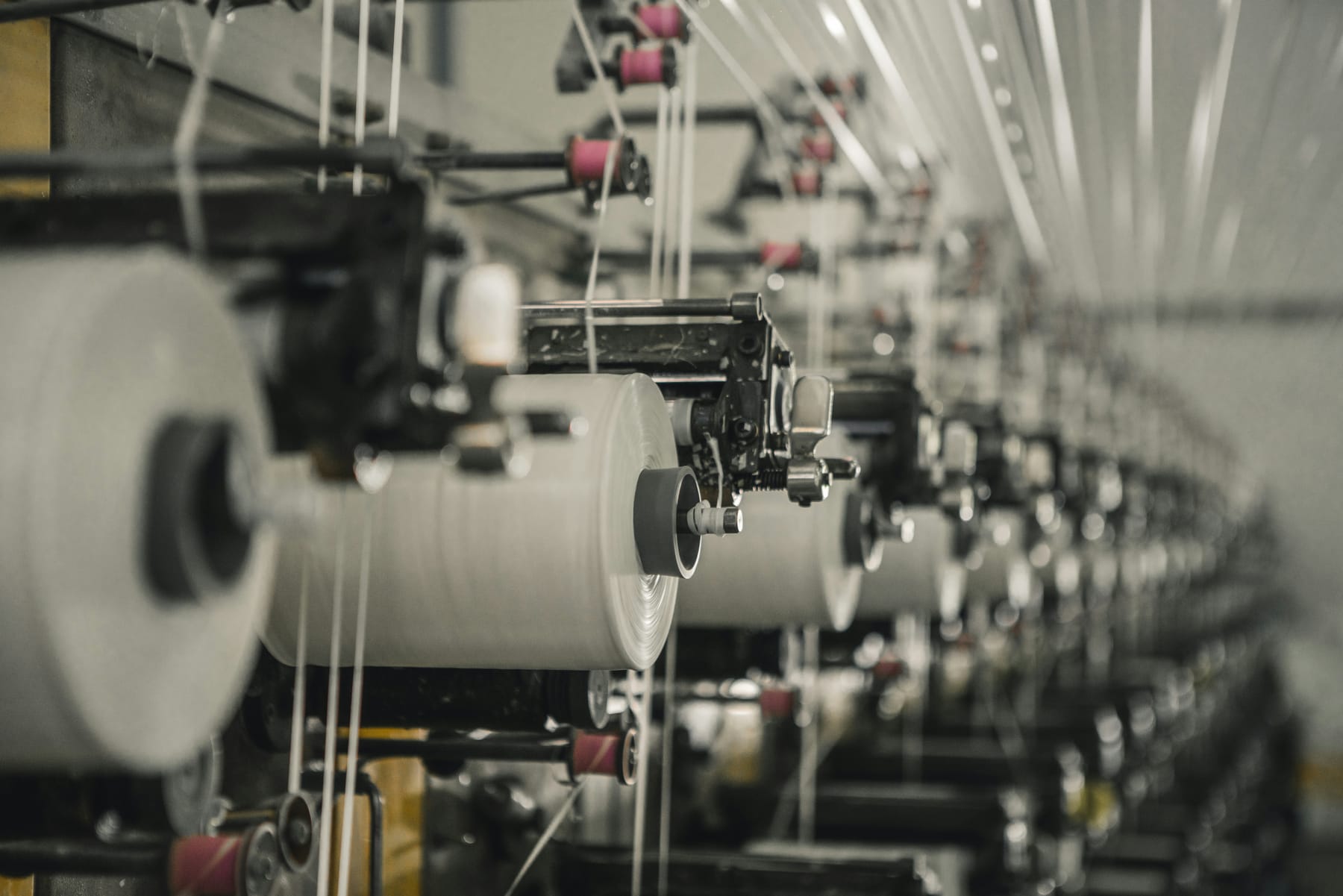 Rows of white yarn cones on winding machines in a textile mill.